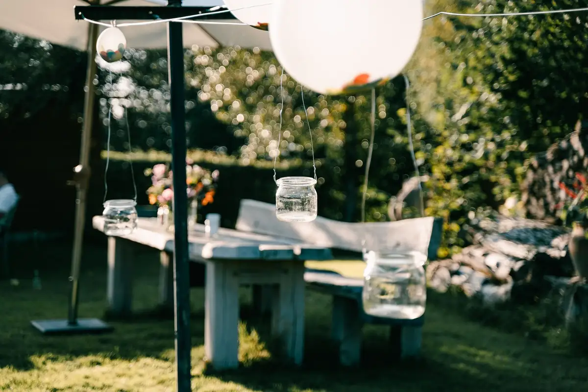 Een lange tafel in de tuin met lantaarns in weckpotten en een ballon erboven.