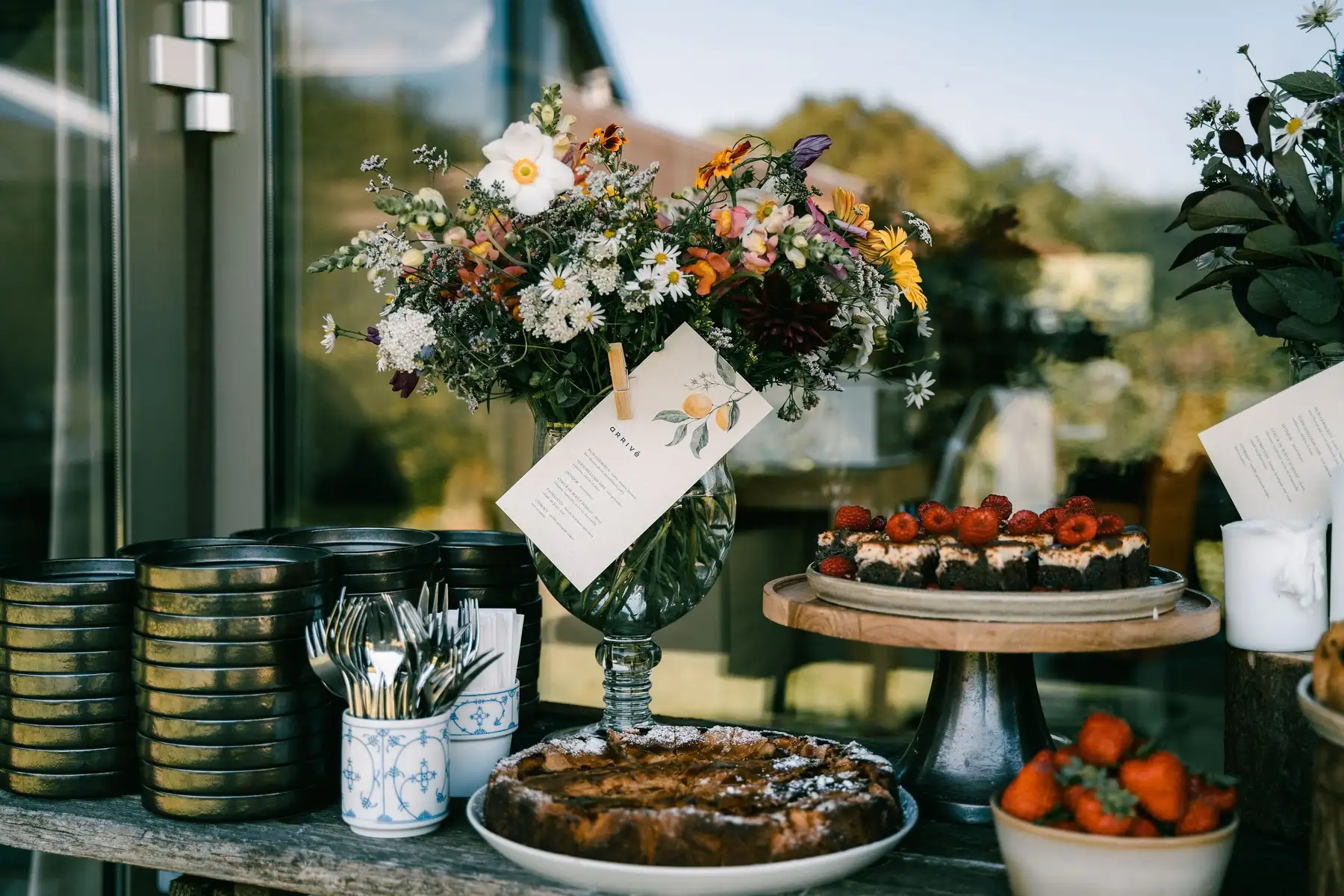 Dessertbuffet met veldbloemen, servies en een menukaartje met citroentak.