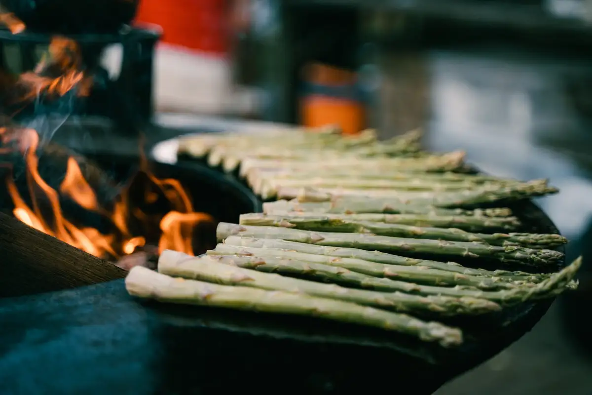 Groene asperges boven een open vuur.